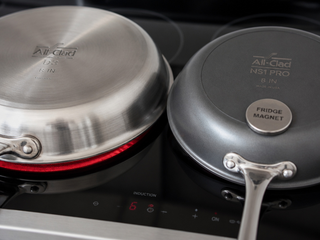 All-Clad stainless steel and nonstick pan bases tested on an induction cooktop.